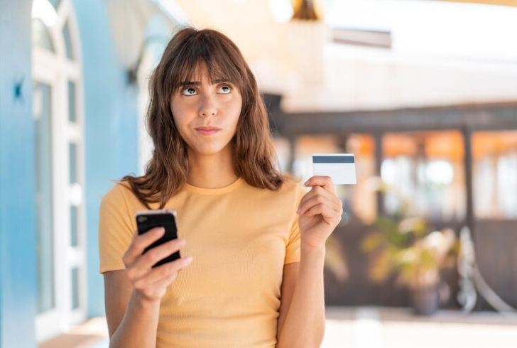 A thoughtful person holding a credit card
