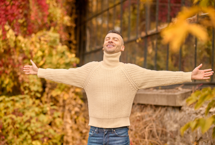 Man smiling with open arms in autumn nature