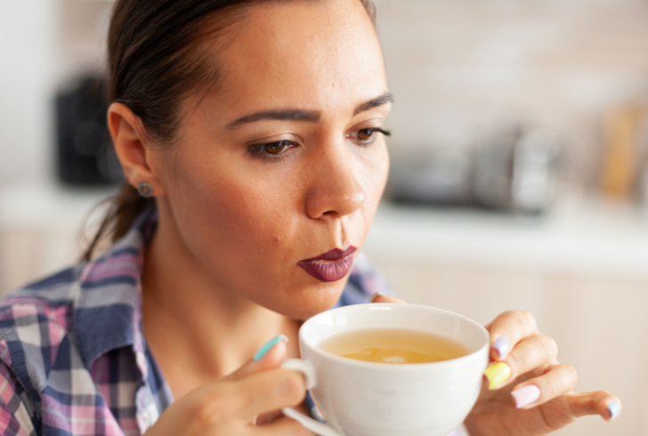 Woman drinks green tea as part of the teamaxxing wellness trend.